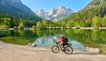 active senior woman on a mountain bike tour at Lake Jezero Jasna in the Triglav National Park near...