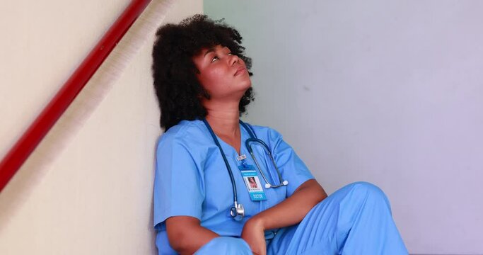 tired exhausted intern nurse or doctor woman sitting on stairs at  hospital. healthcare and medicine concept