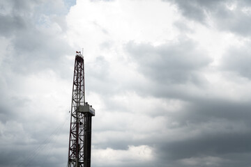 Obraz premium The oil drilling rig derrick structure on cloudy sky background, oil field industrial operation equipment. Selective focus.