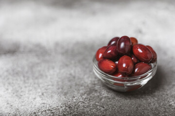 Red olives on a marble background. Various types of olives in bowls and olive oil with fresh olive leaves. Copy space. Place for text. Mediterranean food. Vegan.