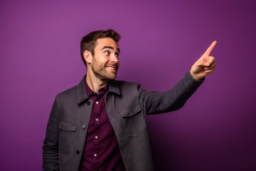 Lifestyle portrait photography of a beautiful boy in his 30s pointing empty space against a vibrant purple background. With generative AI technology