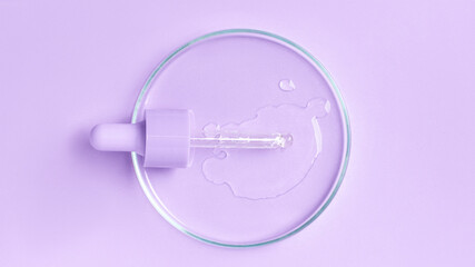 Cosmetic pipette with gel, serum and serum in a Petri dish on a purple background