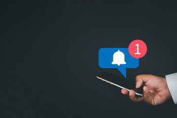 Reminder,digital marketing,business concept.,Close up of hand using smartphone with Bell Notification icon on black background with copyspace suitable for internet,application,e-mail,technology idea.