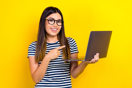 Photo Of Young Cheerful Programmer Chinese Woman Pointing Finger Her New Hp Netbook Modern Gadget Isolated On Yellow Color Background