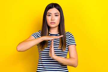 Obraz premium Photo portrait of focused calm korean girl black hair hands showing timeout sign stop game rules isolated on yellow color background