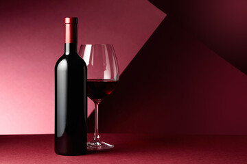 Bottle and glass of red wine on a red background. - Powered by Adobe