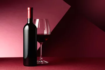 Fotobehang Bottle and glass of red wine on a red background. © Igor Normann