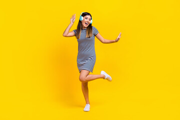 Fototapeta na wymiar Full length photo of excited sweet woman dressed striped outfit headphones dancing having fun isolated yellow color background