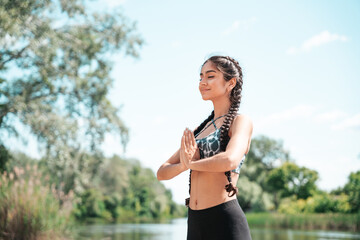 Pretty Indian yogi woman practicing yoga holding her palms together and meditating