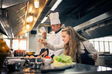 Apprentice chefs are cooking in the kitchen in a cooking school. - obrazy, fototapety, plakaty
