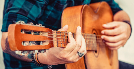 Male musician playing guitar, music instrument. Man's hands playing acoustic guitar, close up....