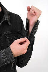 a man in a black denim jacket shows how to fasten a sleeve with a zipper