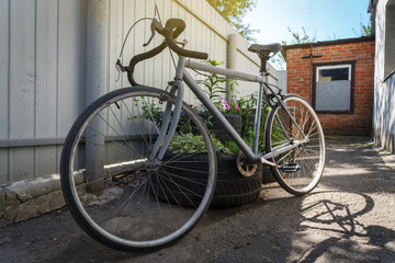 Fototapeta na wymiar old sports gray bicycle in the summer in the yard in the sunlight