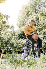 Family picnic. Dad and son in a green garden in sunny weather playing on a picnic. Front view