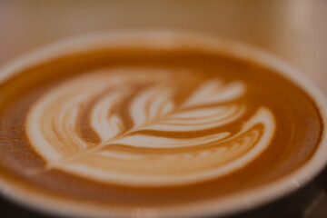 Close up a cup of hot latte art coffee on wooden table.A cappuccino is an espresso-based coffee drink with steamed milk foam.Best of menu in the coffee shop or restaurant.