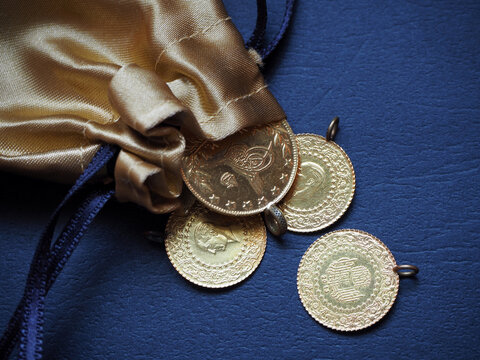 A pouch of gold coins. Old Turkish golds and new Turkish golds isolated on black background. 