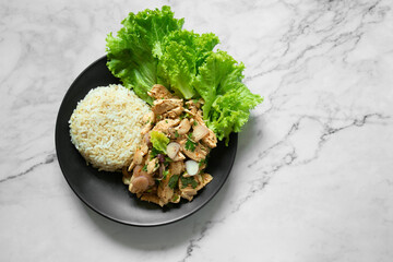 Spicy boiled chicken breast fillet with chilli powder and shallots seasoned with salt. Brown rice and vegetables on a black plate placed on a marble, healthy, weight loss, clean food.