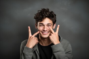 Headshot portrait photography of a happy boy in his 20s making a gesture of i'm thinking with the finger on the head against a metallic silver background. With generative AI technology