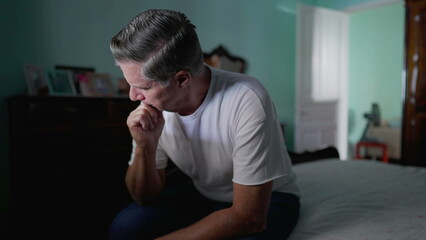 Anxious preoccupied older man sits by bedside feeling worry. Stressed desperate middle-aged person...