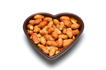 White heart shaped bowl with dried fruit mix (peanuts, walnuts, hazelnuts), isolated on white background.
