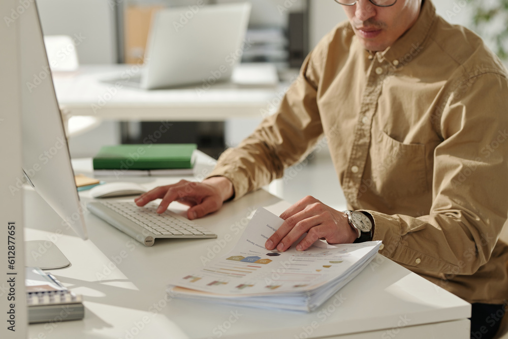 Aufkleber cropped shot of young businessman in beige shirt working with financial documents and using computer