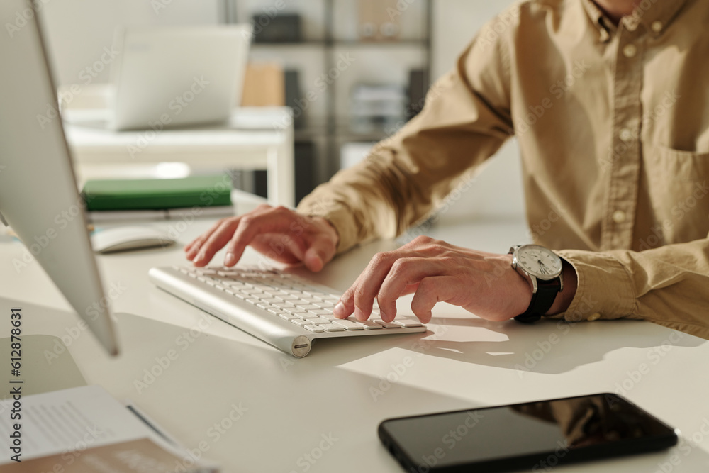 Aufkleber Focus on hand of young businessman pressing buttons of computer keyboard while working with online data or communicating in messenger