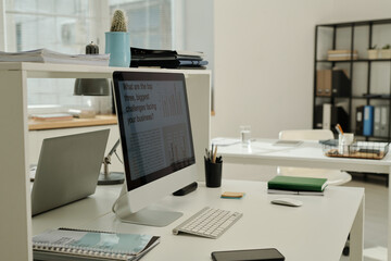 Workplace of white collar worker with computer monitor, keyboard, notebook, financial documents, smartphone and mouse on desk