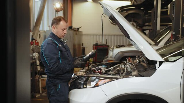 Auto service, maintenance concept. Mechanic checks the car, making diagnostics with laptop at the service station. Service maintenance of industrial to engine repair. OBD is On Board Diagnostics.