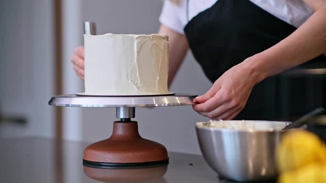 Housewife in black apron making delicious cake covered with white mastic for wedding celebration woman enjoying preparing organic homemade confectionery in modern kitchen