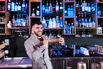 Young mixologist shaking a cocktail for his demanding clients. Concept: drinks, consumption, nightlife