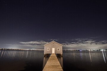 Panoramic view from the jetty of a lakehouse with the cityscape in the background at night