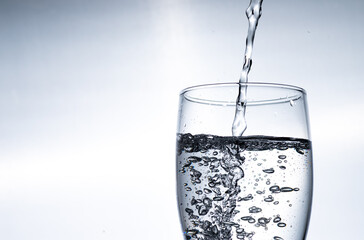 Water is poured into a glass from above