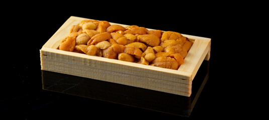 Bafun urchin or uni in wooden box on dark background, Uni sushi or sashimi ingredients, Japanese...