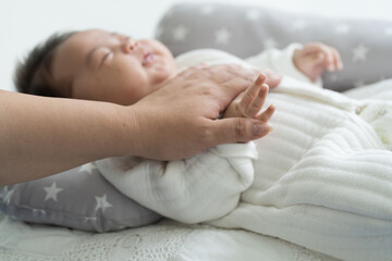 Fototapeta na wymiar Hand of mother holding newborn baby finger on white bed