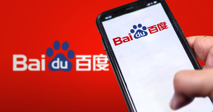 A hand holding a phone with the Baidu website on the screen