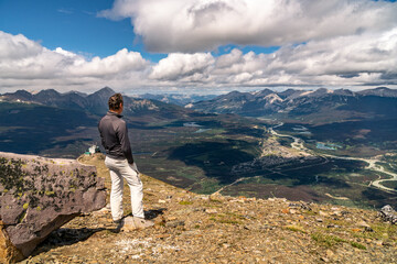 Fototapeta premium Mature Caucasian man watching the town of Jasper from the top of a mountain, Whistlers Peak, Jasper National Park, Canada