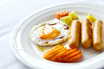 Breakfast includes fried eggs, hot dogs, and carrots.