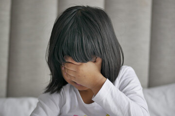 a upset child girl cover her face with hand 