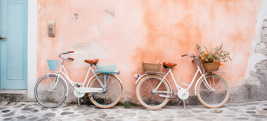 two vintage bicycles leaning against a wall, in the style of serene oceanic vistas. Wicker basket with artificial flowers on the bike.