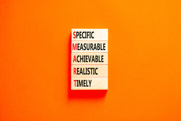 SMART symbol. Concept words SMART specific measurable achievable realistic timely on wooden block. Beautiful orange background. Business SMART specific measurable achievable realistic timely concept.