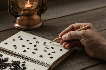 hand with a pencil, English letters on the page in a notebook, creative crisis, retro style