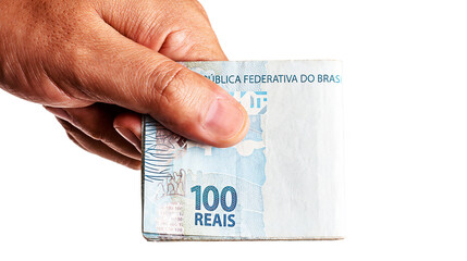 hand holding several banknotes of one hundred reais from Brazil, on isolated white background. Bank draft or financial profit concept