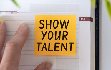 Show your talent text on light orange post-it paper pinned on notebook and hand. This message can be used in business concept about talents.