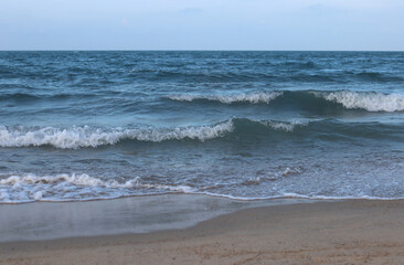 Sandy beach with waves at evening