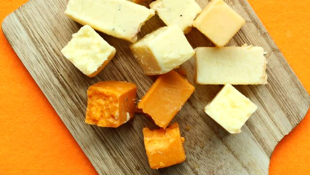 Cheese cubes green, yellow and red color on chopping board 