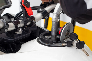 Gloved hand of a biker pouring gasoline into the tank of his motorcycle