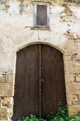 Obliquely carved brown wooden old door on old stone wall with wooden lattice window above in Kyrenia or Girne old town, Northern Cyprus.