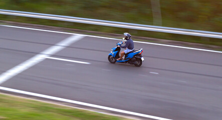 Fototapeta premium man driving scooter on road