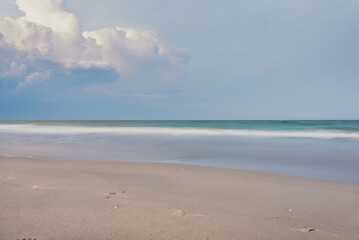 Long exposure of waves crashing on beach with clouds in sky 