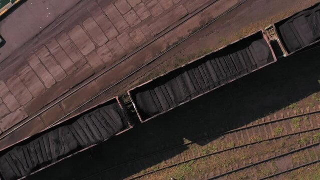 Slowly moving cargo train with loaded black coal. Aerial top drone view.